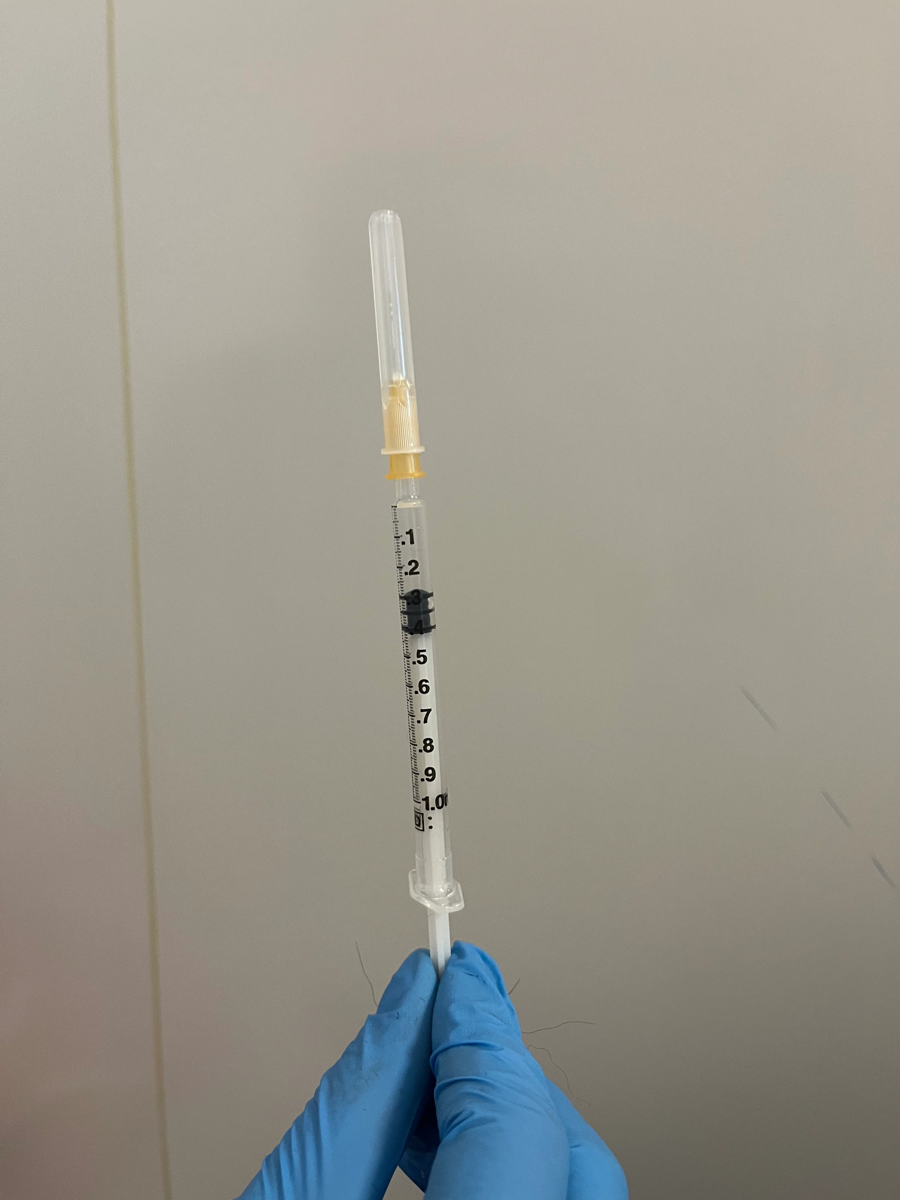 A syringe held by a gloved hand.