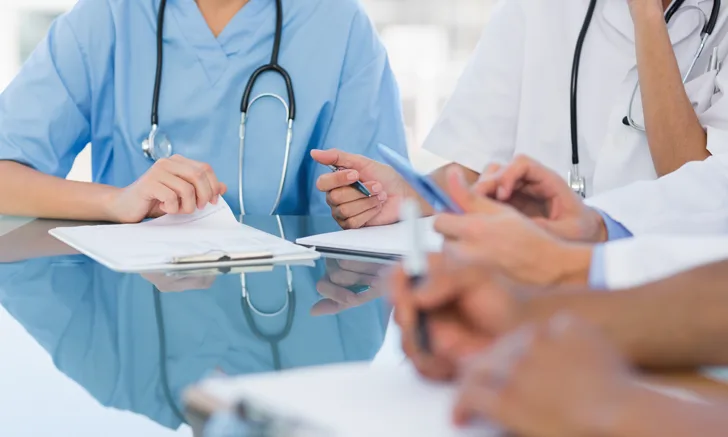 A group of veterinary professionals sitting at a desk with pens and clipboards.