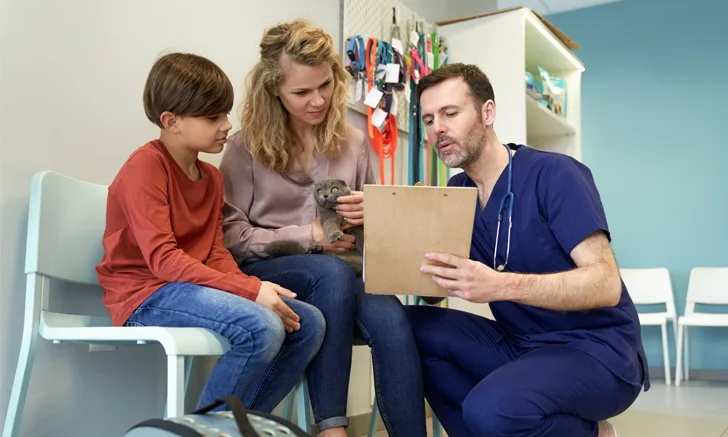 male veterinarian showing a clipboard to cat owner