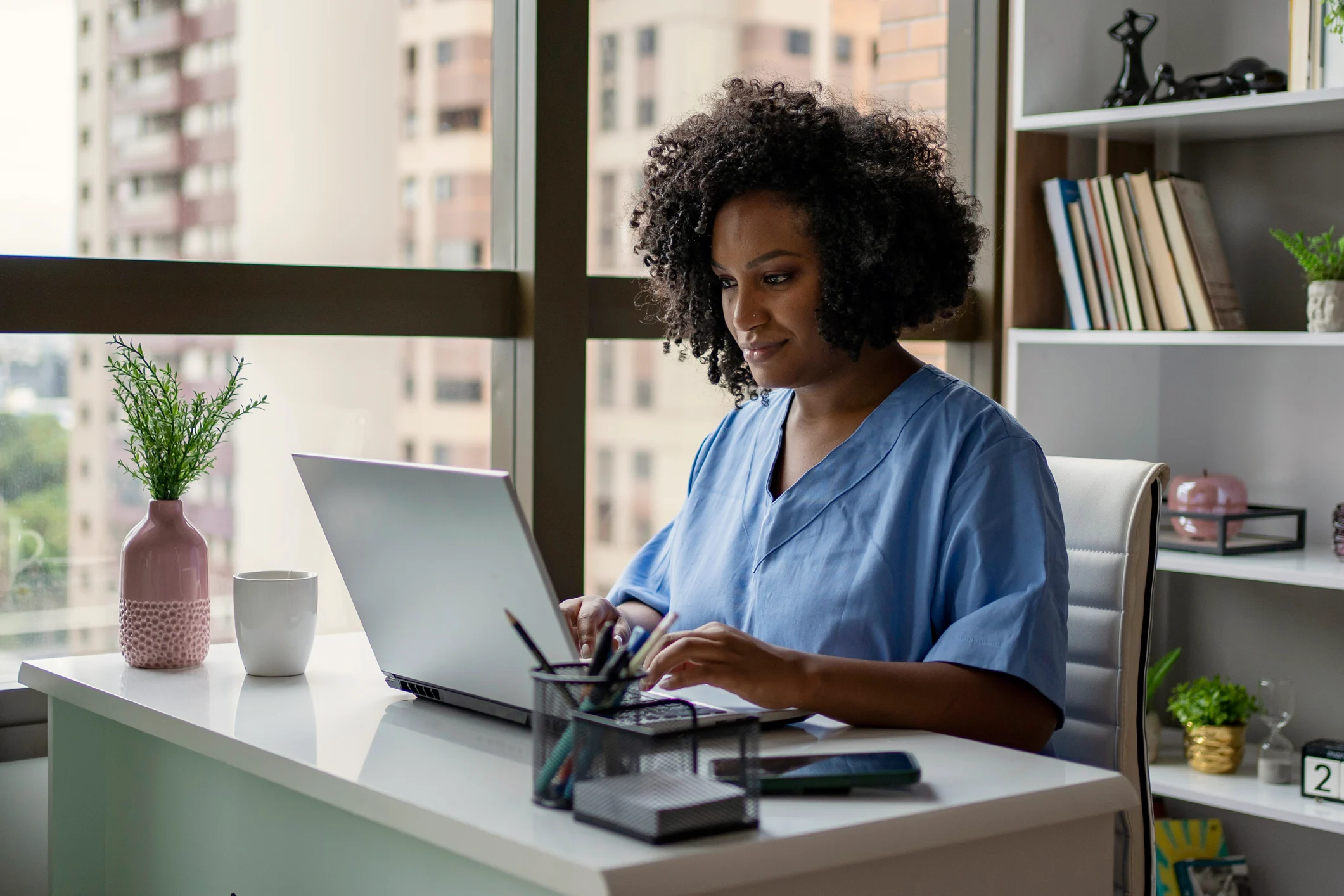 A veterinary professional typing on a laptop at a desk.