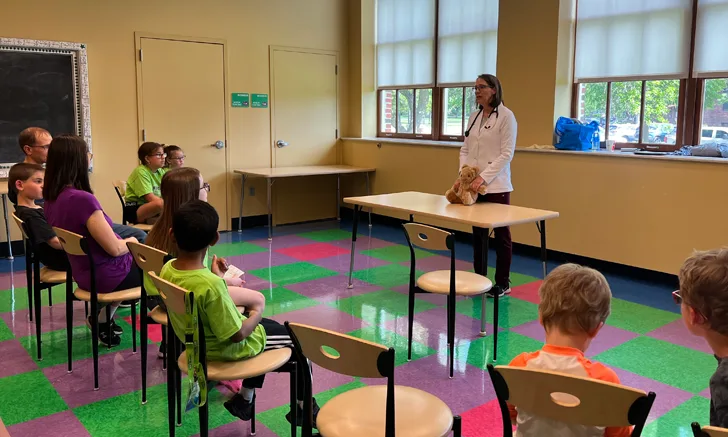 a veterinarian stands in front of a group of children ready to learn