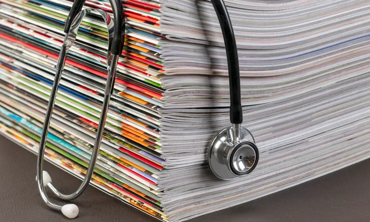 A stack of magazines with a stethoscope draped over them.