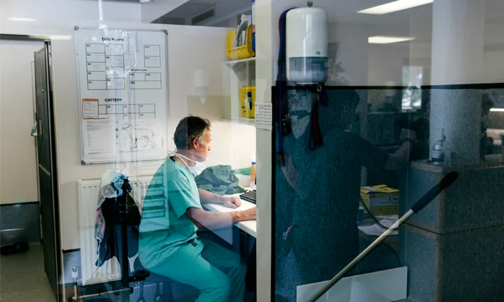 a veterinarian sits at a desk in an empty clinic