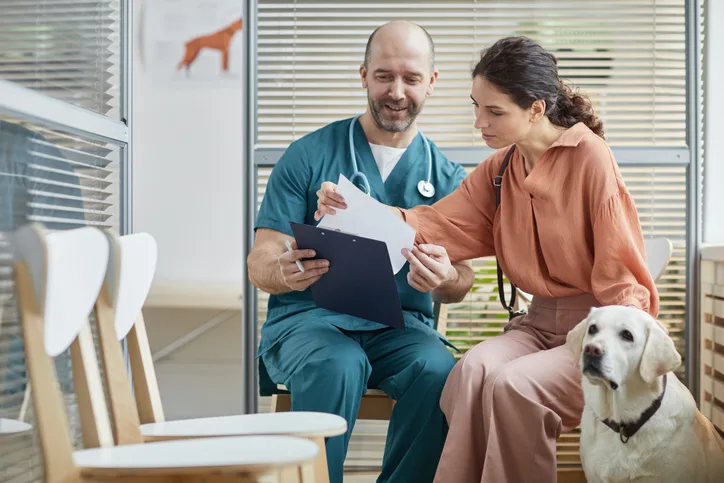 Veterinary professional going over paperwork with a client in a veterinary clinic. 