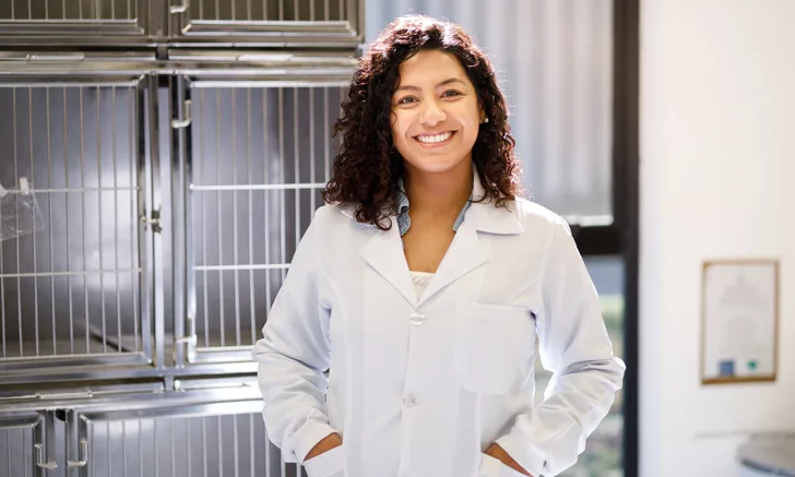 a veterinarian smiles in front of an empty kennel