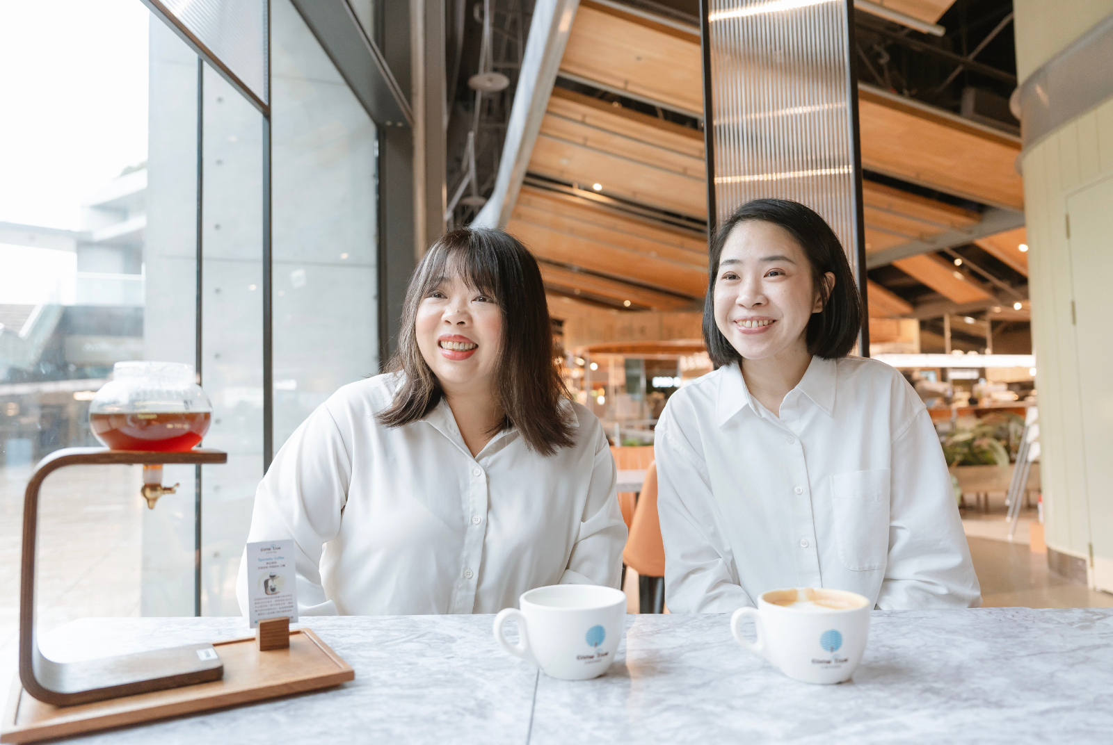 台北誠品松菸店店經理周筱茜(右)與成真咖啡訓練人資部協理鄭玉婷(左)，透過 NUEIP 系統解放行政時間，現在他們有更多時間可以將注意放到更值得的事務上。