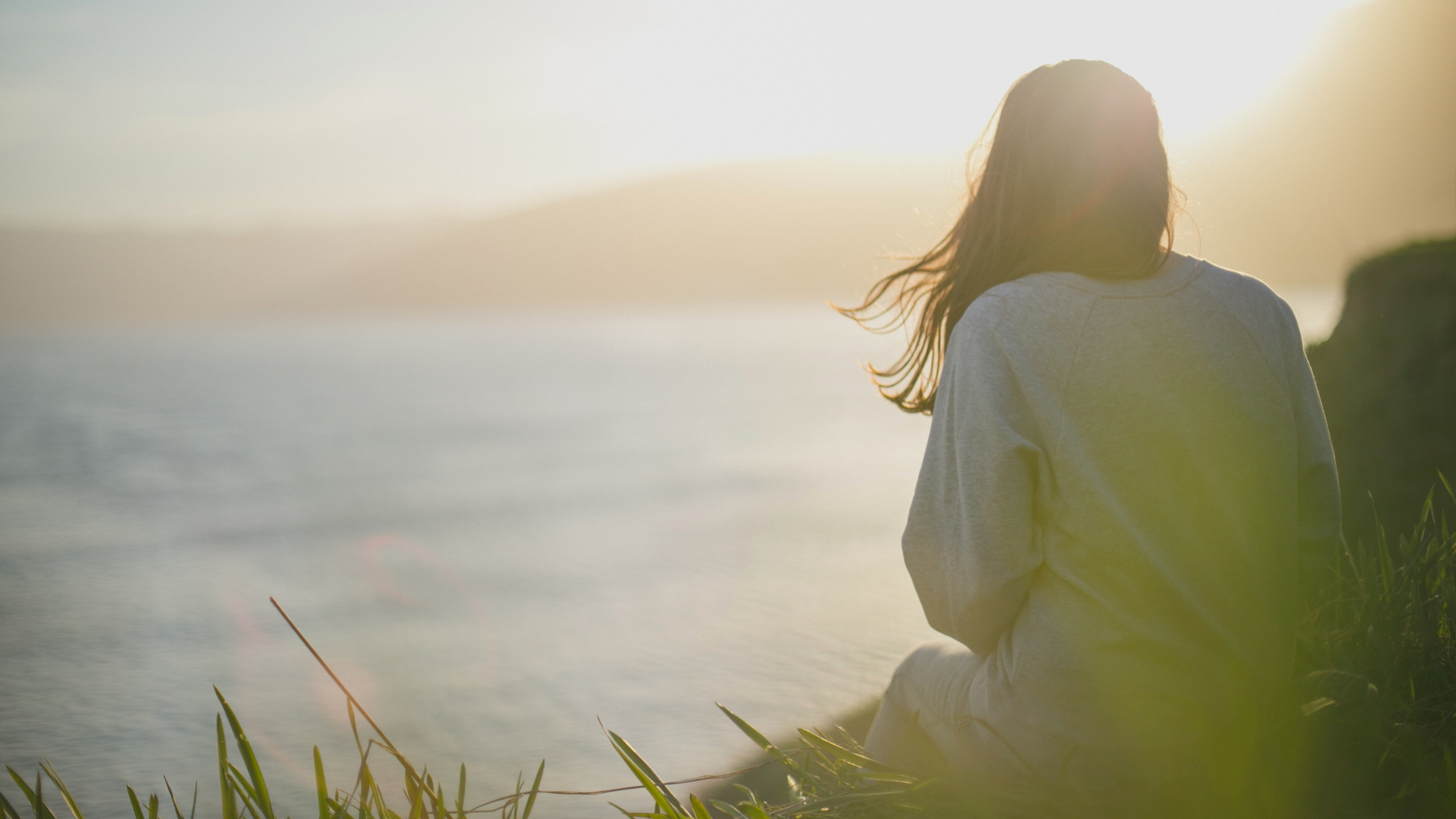 Person in Nature Looking out over Body of Water at Sunset