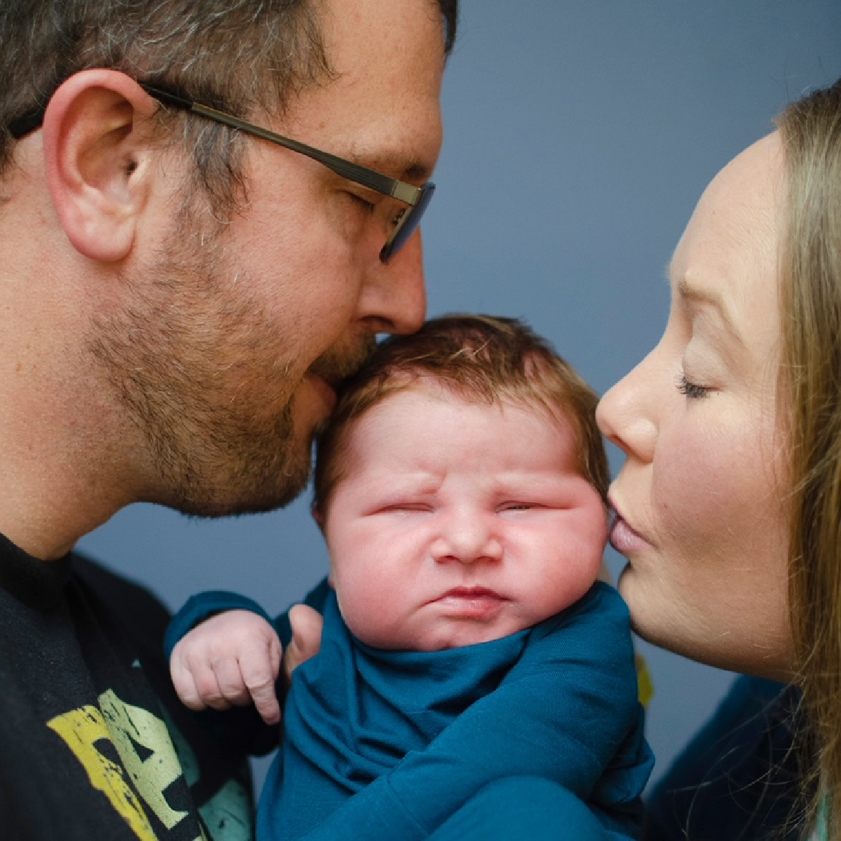 Kirsten Kozak and her husband are pictured kissing their newborn son.