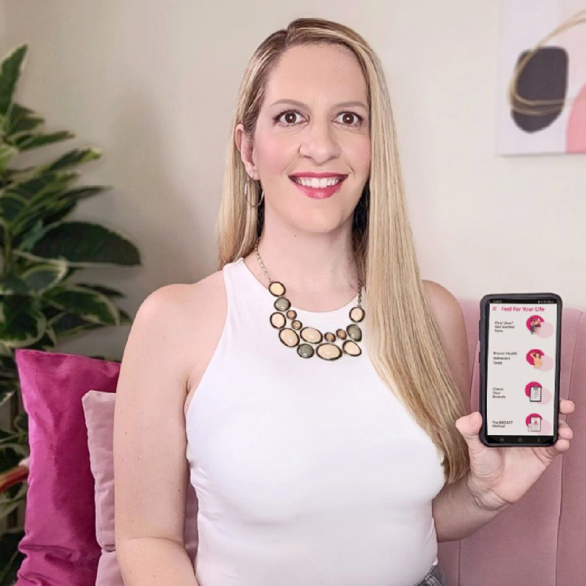 Jessica Baladad is pictured holding a cellphone displaying her breast cancer awareness app.