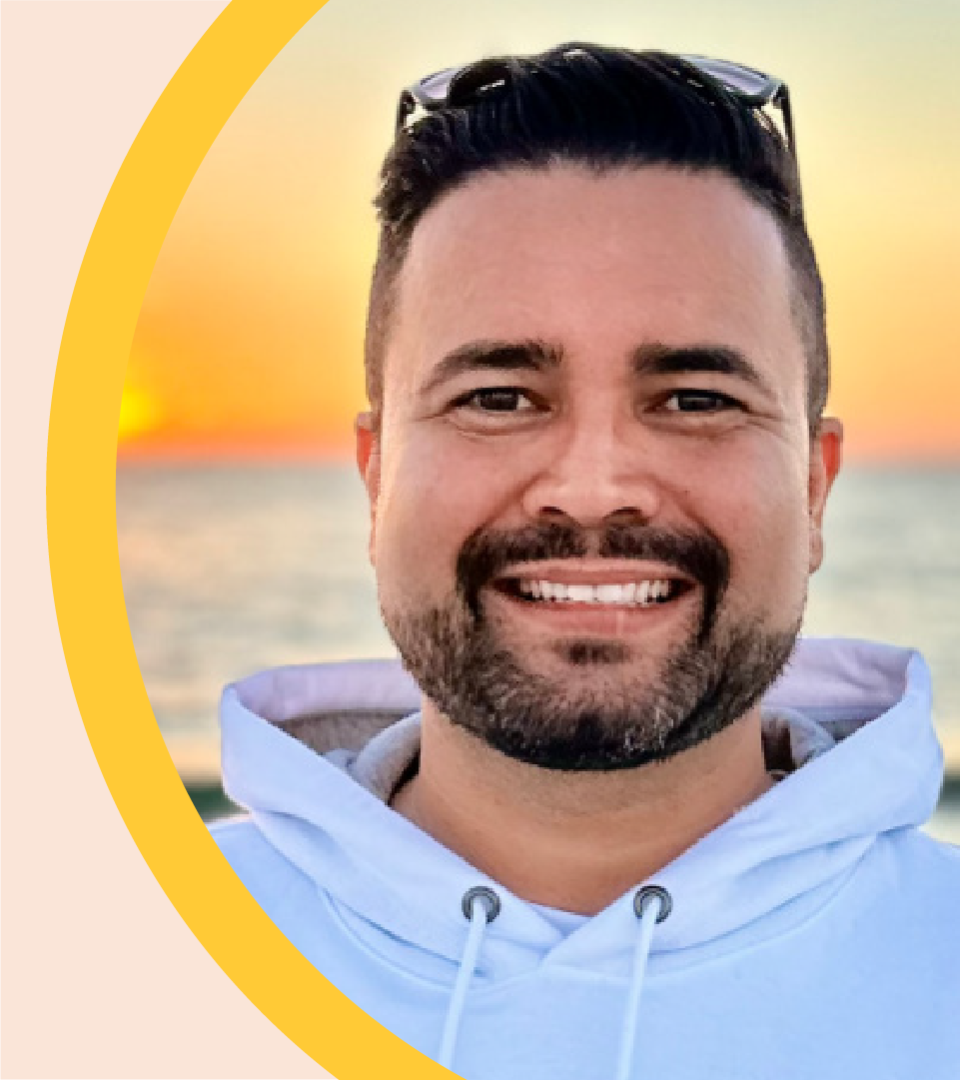 Ricardo Louzada is pictured outdoors, with the sun setting behind him.