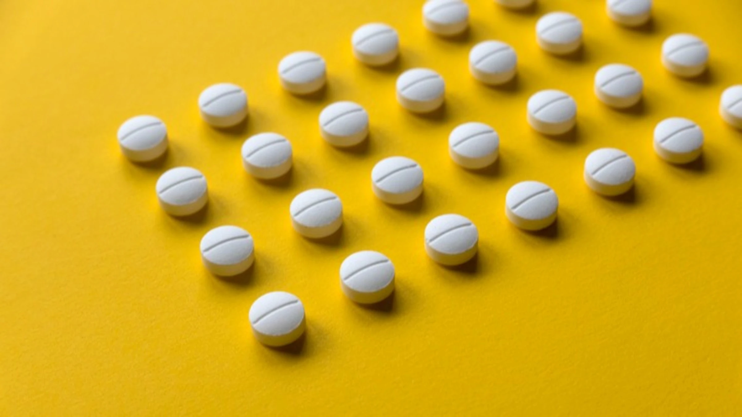 Sección de pastillas redondas blancas colocadas en diagonal sobre un fondo amarillo brillante.
Mohamad Faizal Bin Ramli/iStock vía Getty Images
