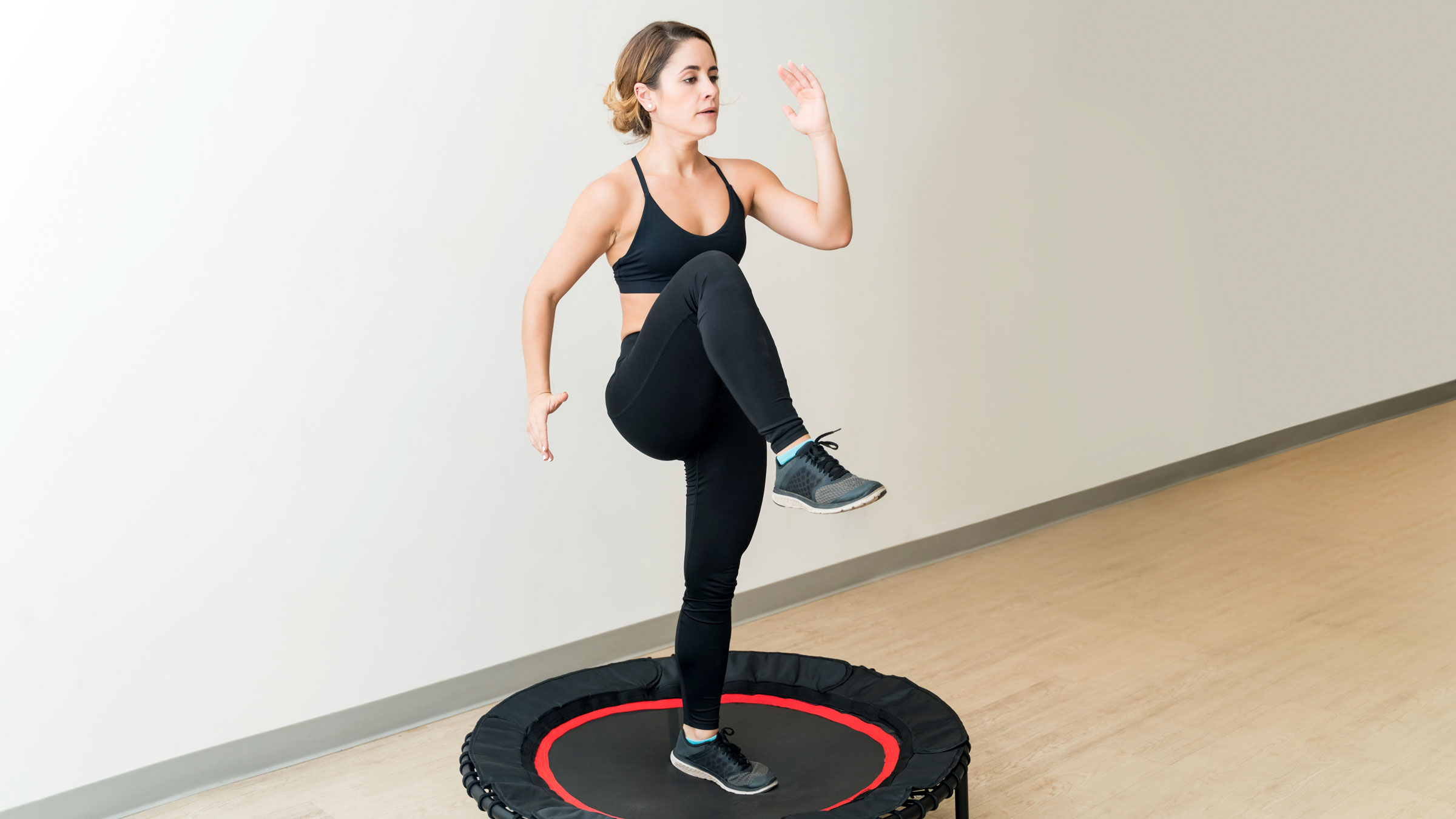 A woman balancing on one leg on a mini trampoline