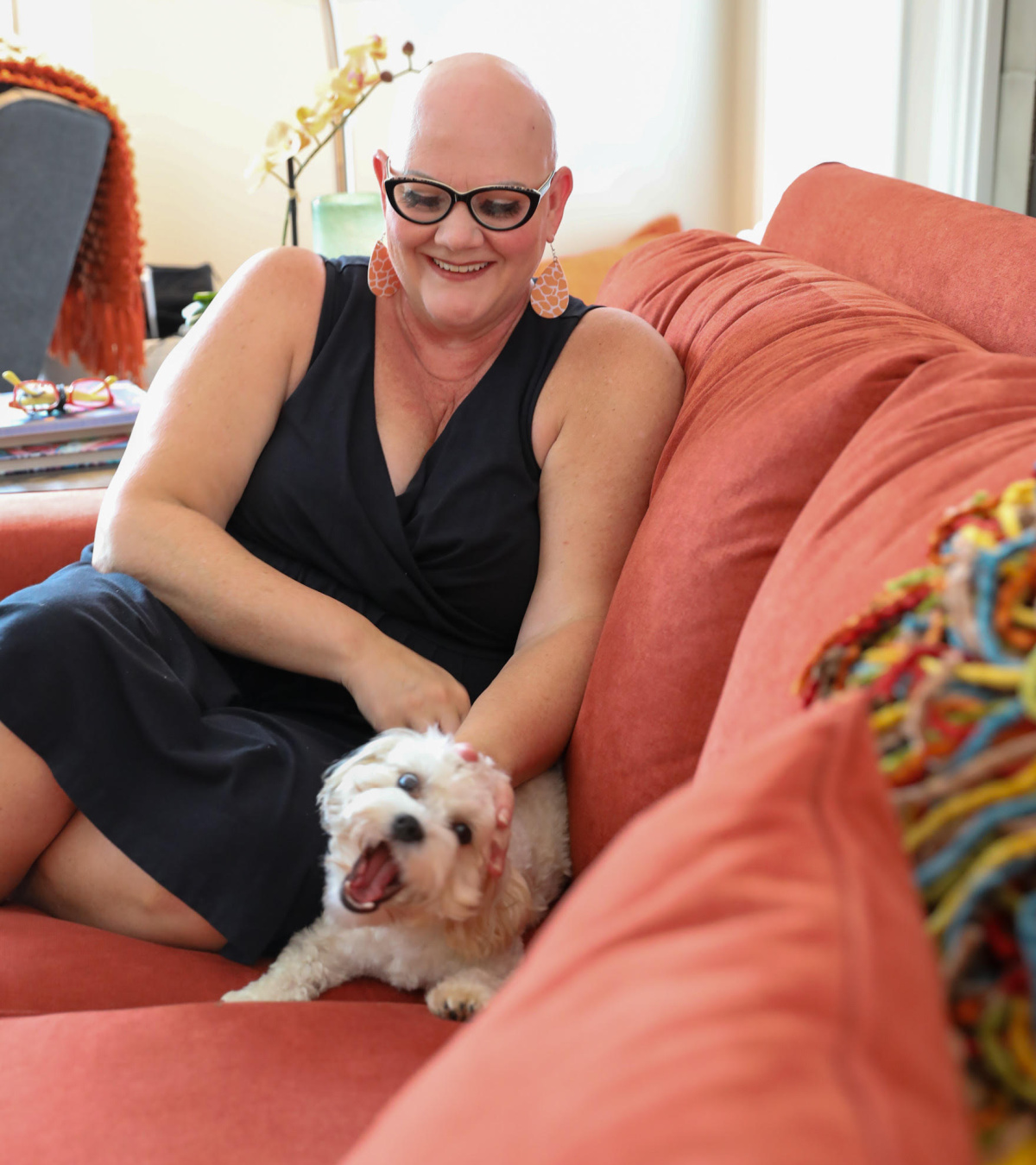 Christie Cox is pictured sitting on her couch with her dog.