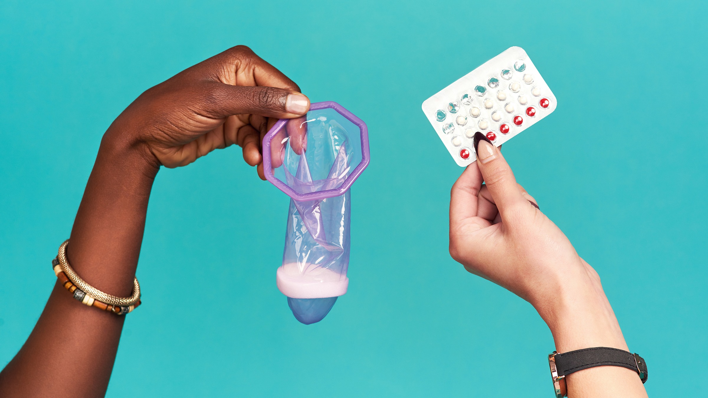 Cropped shot of two arms coming into frame holding different types of contraceptives. One is holding a birth control pill pack and the other is holding a condom.
PeopleImages/iStock via Getty Images