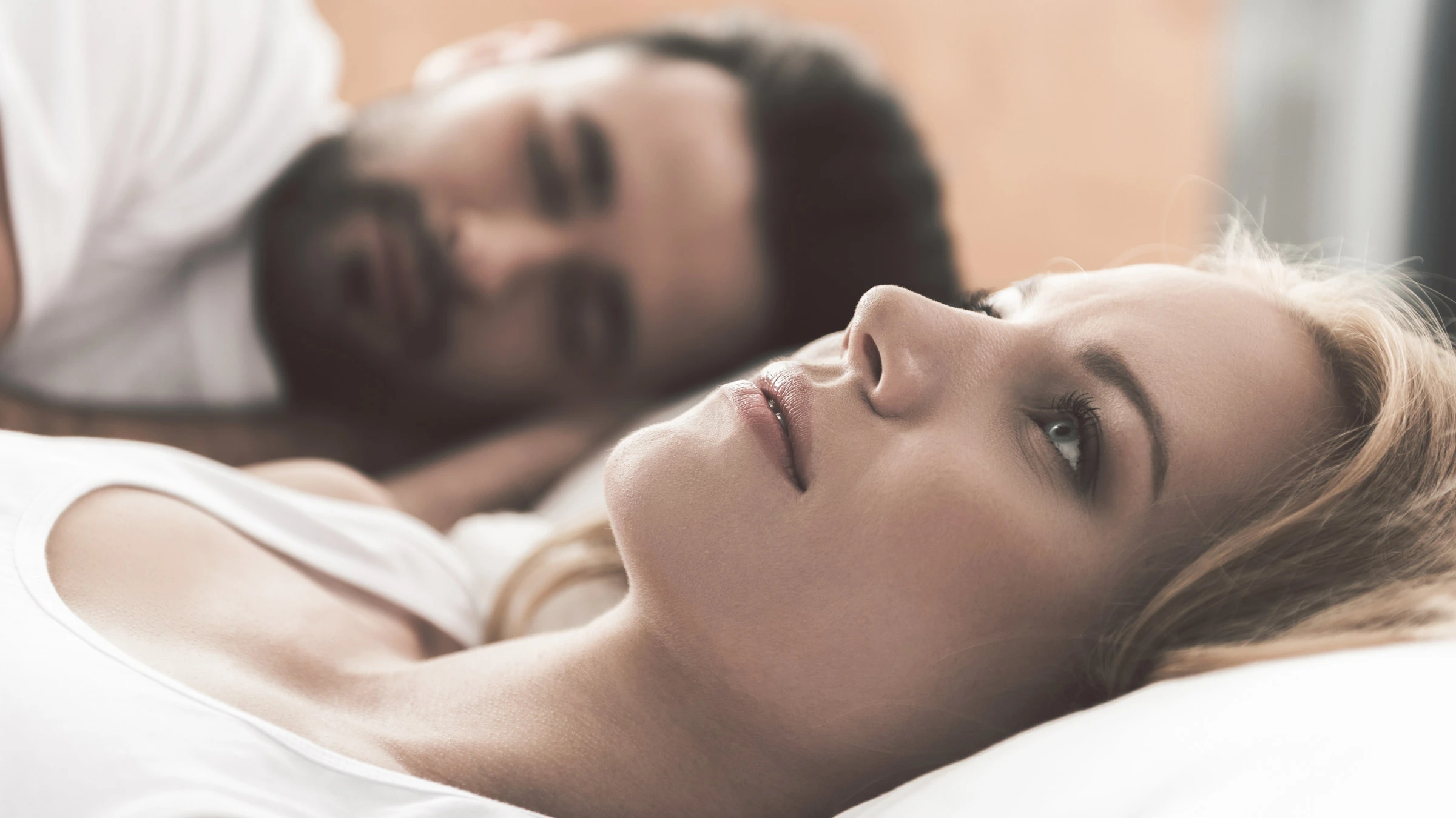 A person lying awake next to their sleeping partner.
YakobchukOlena/iStock via Getty Images Plus 