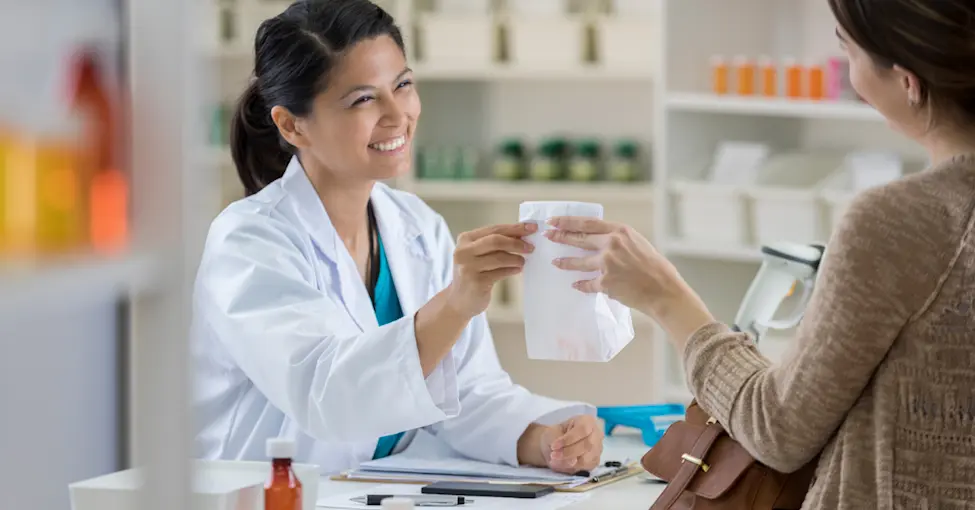 Female pharmacist checking out a customer