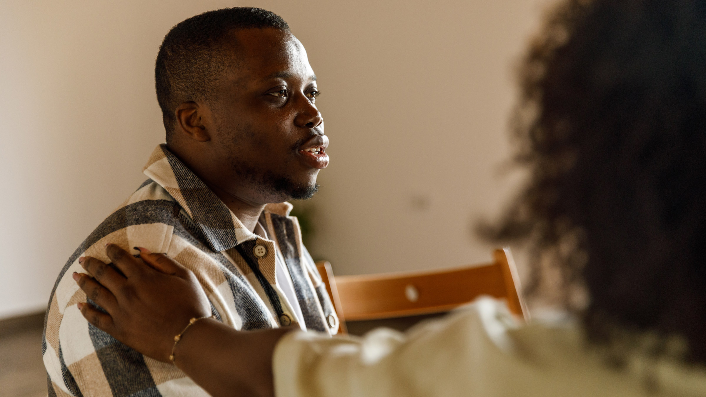 A Black man talking in group therapy, being comforted by the participant sitting next to him.
master1305/iStock via Getty Images Plus