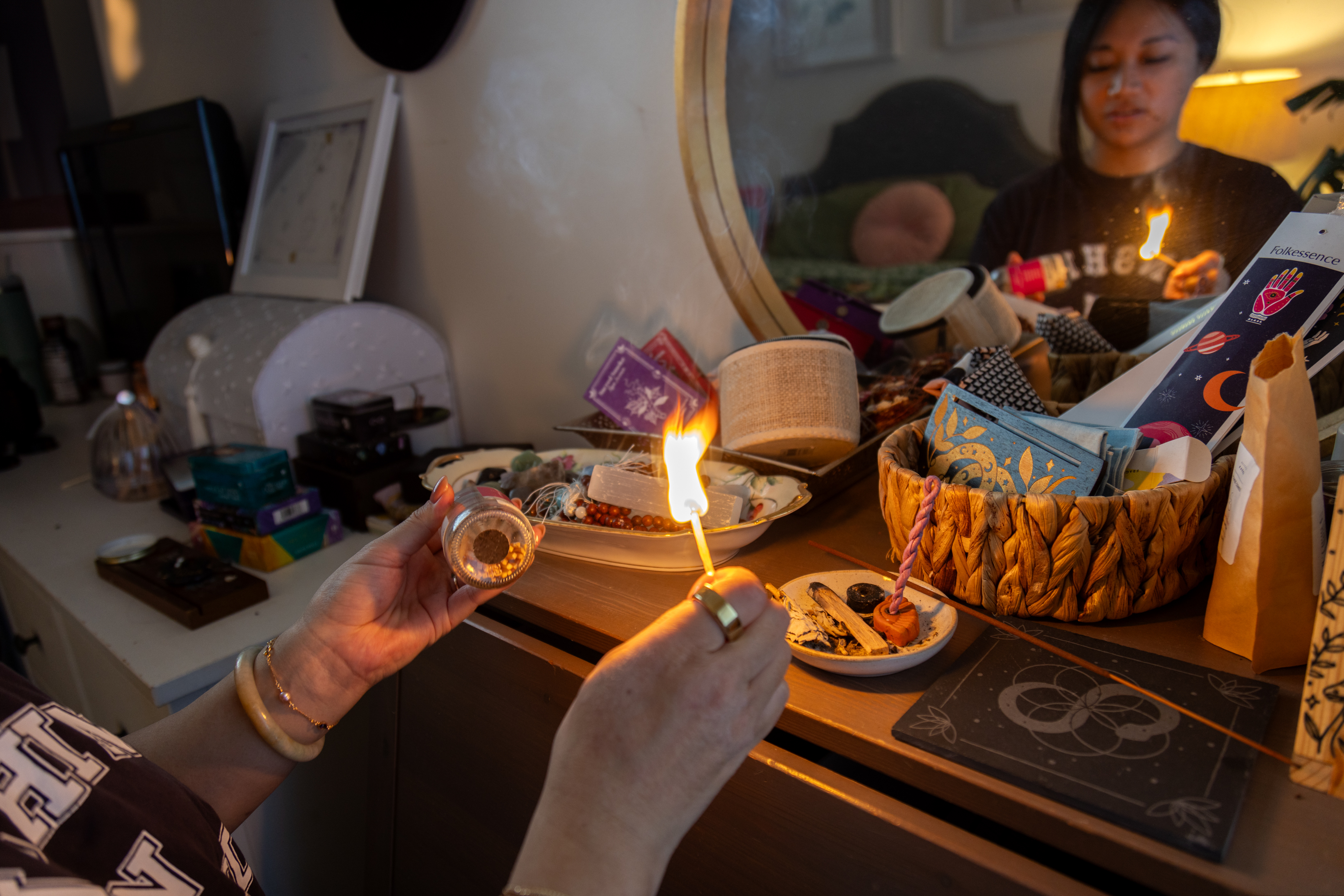 Larisa lights a incense in front of a mirror.