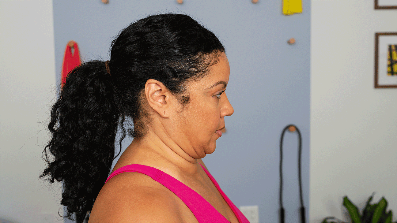 Profile view of woman demonstrating forward neck bend exercise