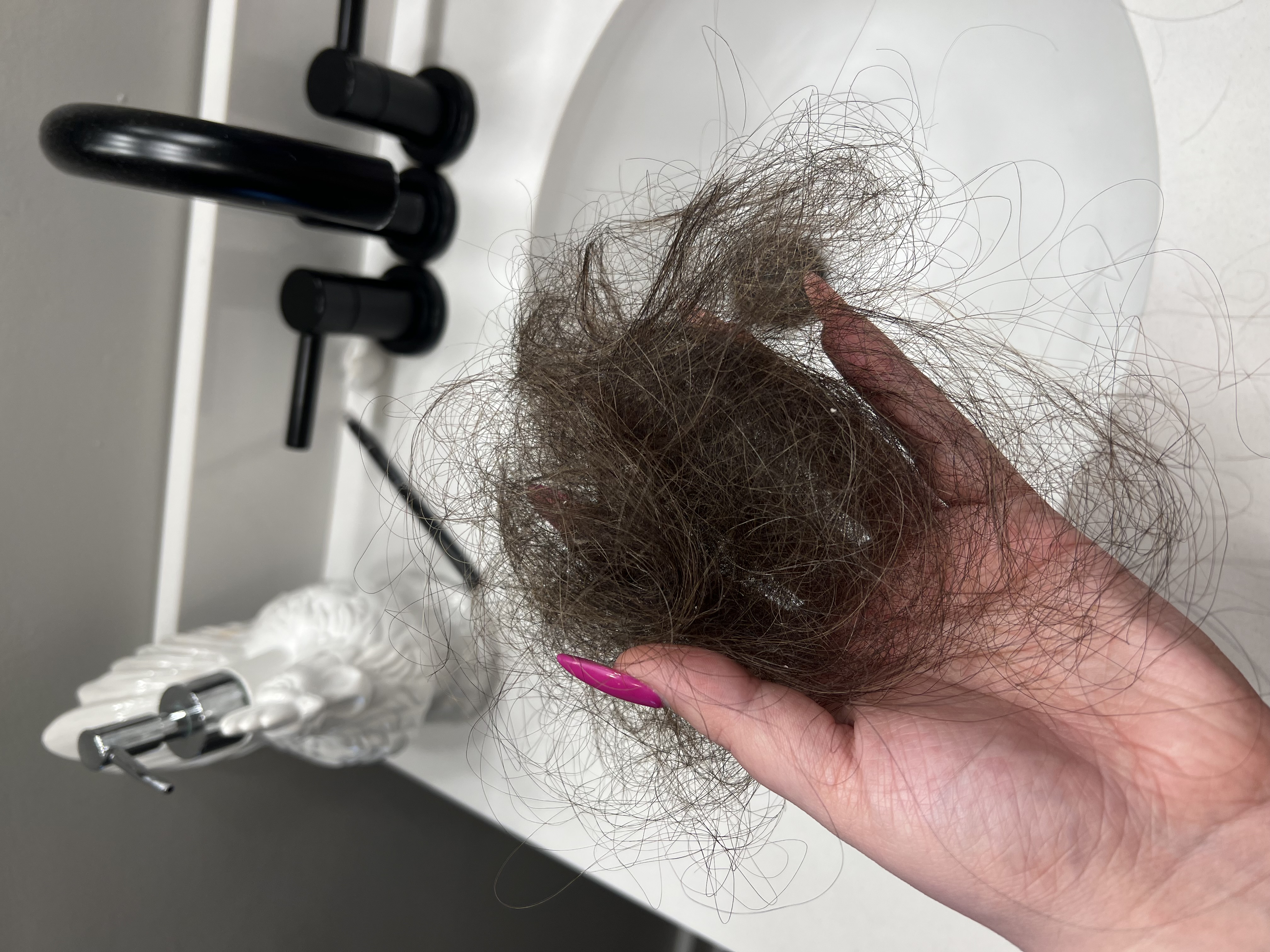 Photo of Michaela Pearson holding a clump of hair over her bathroom sink.