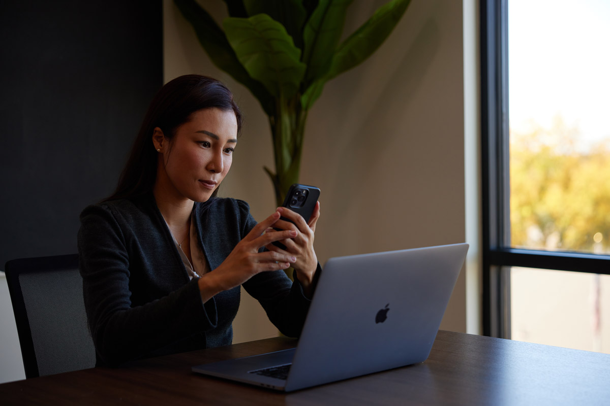 Woman looking at phone and laptop