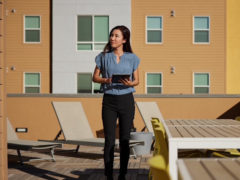 Woman standing with ipad with property in background