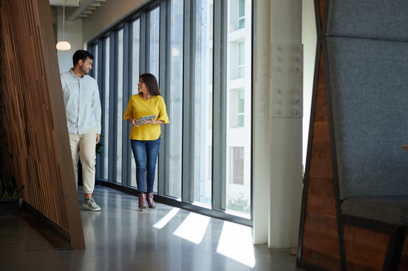 Man and woman walking down hallway with ipad