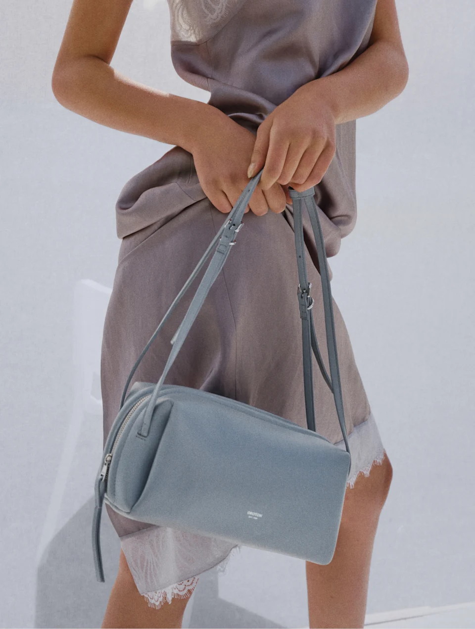 Model holding a blue leather crossbody bag