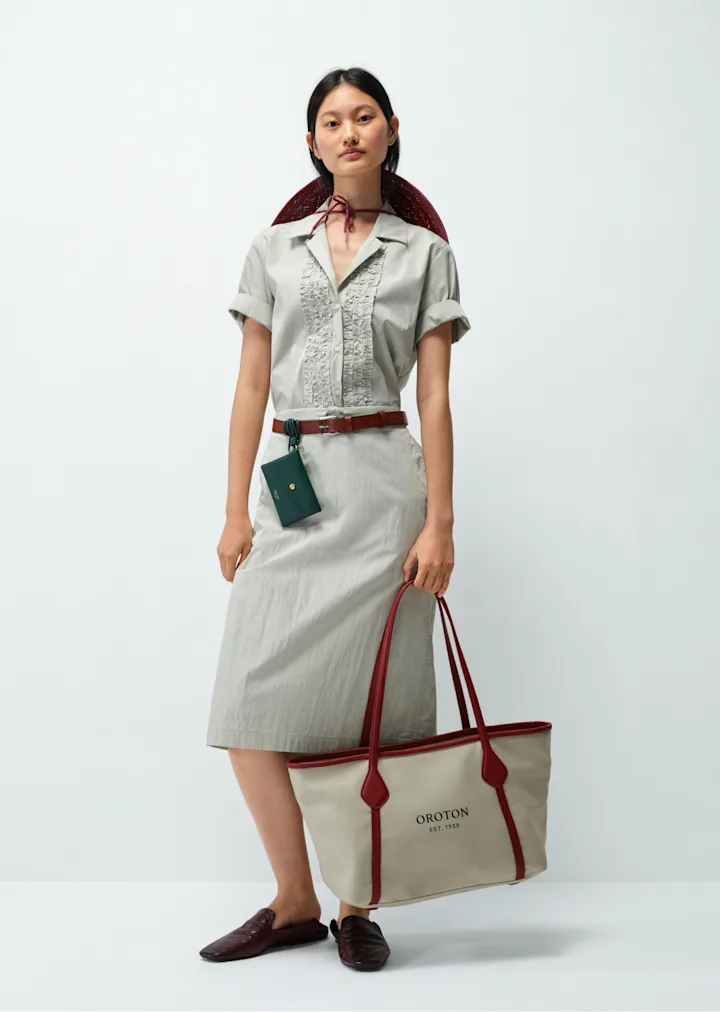 Model in a sage shirt and skirt with a canvas and leather tote