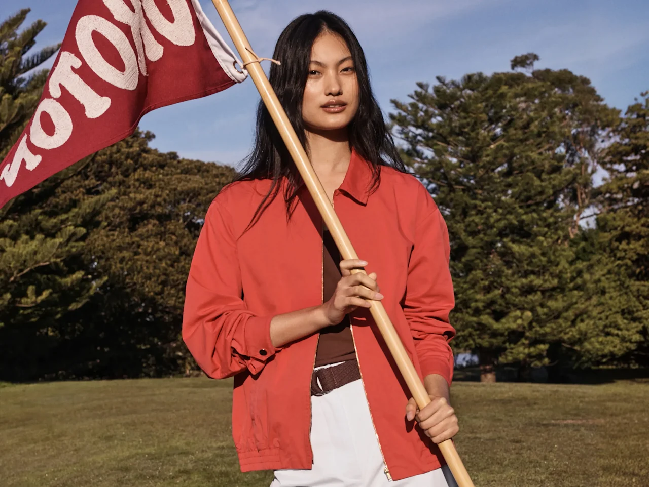 Woman in a red jacket holding an Oroton flag