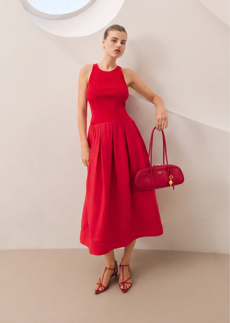 Model in a red sleeveless midi dress carrying a red bag
