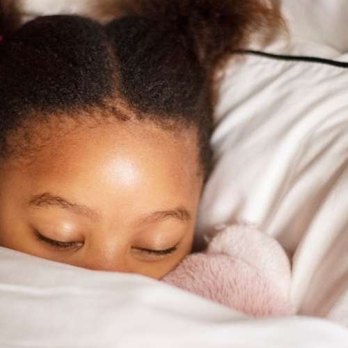 A small child sleeping in a toddler bed.