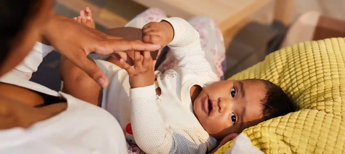 Baby in mom's lap, holding hand | Huckleberry