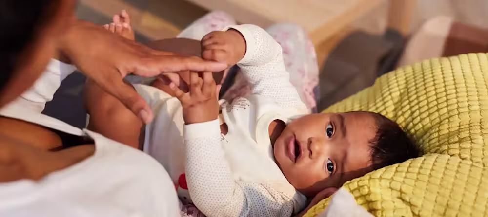 Baby in mom's lap, holding hand
