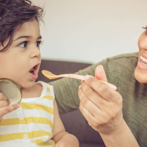 A mother trying to feed her child.