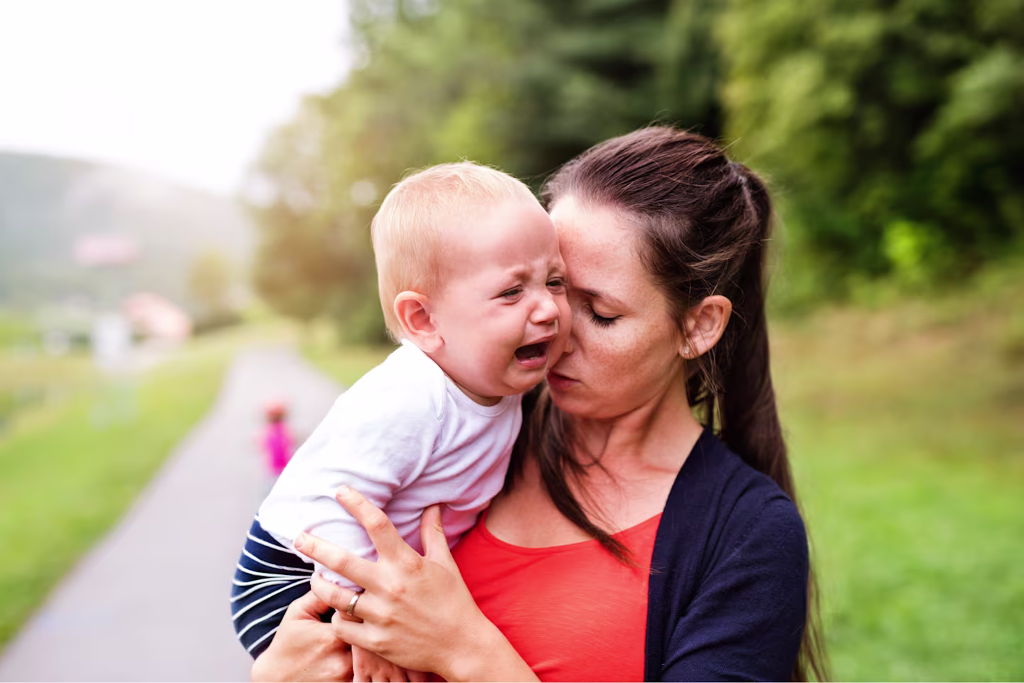 Baby separation anxiety: Baby attached to mom is crying while being carried.