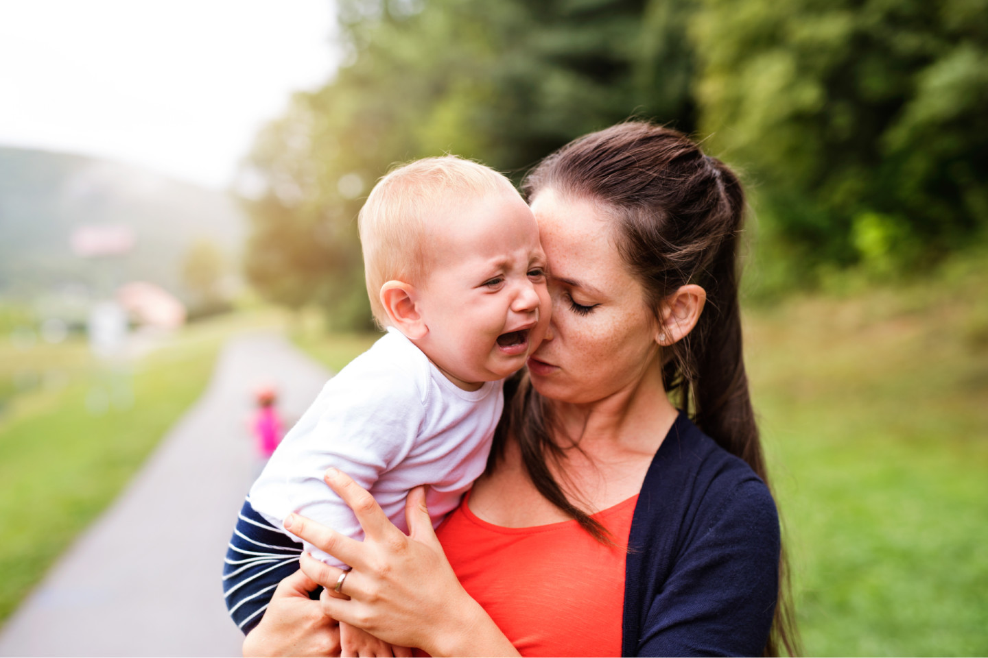 Baby separation anxiety: Baby attached to mom is crying while being carried.