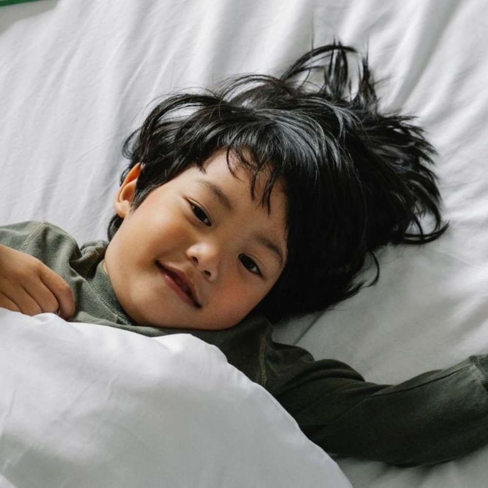 Toddler laying in bed going for a nap.