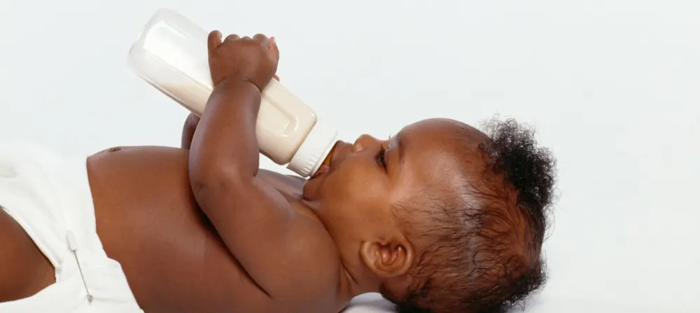 A baby holding a bottle.