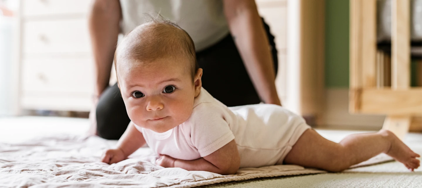 Baby on the floor working on rolling over | Huckleberry