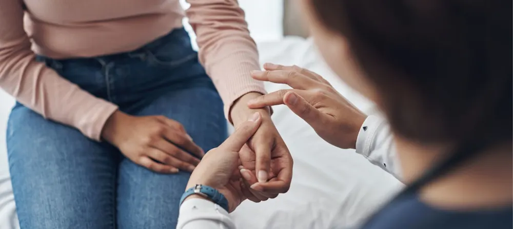 A health worker is checking a woman's wrist.