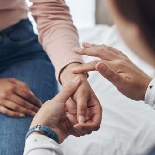 A health worker is checking a woman's wrist. 