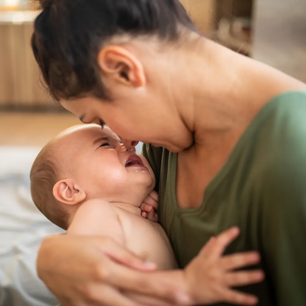 Overtired baby held by mother