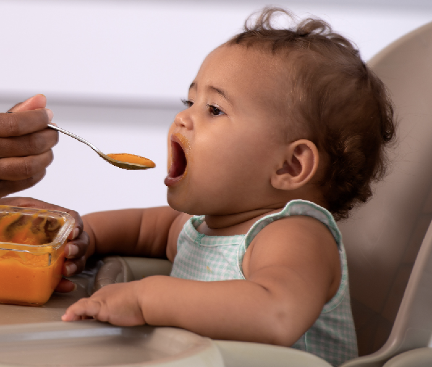 Baby trying solids in a high chair.