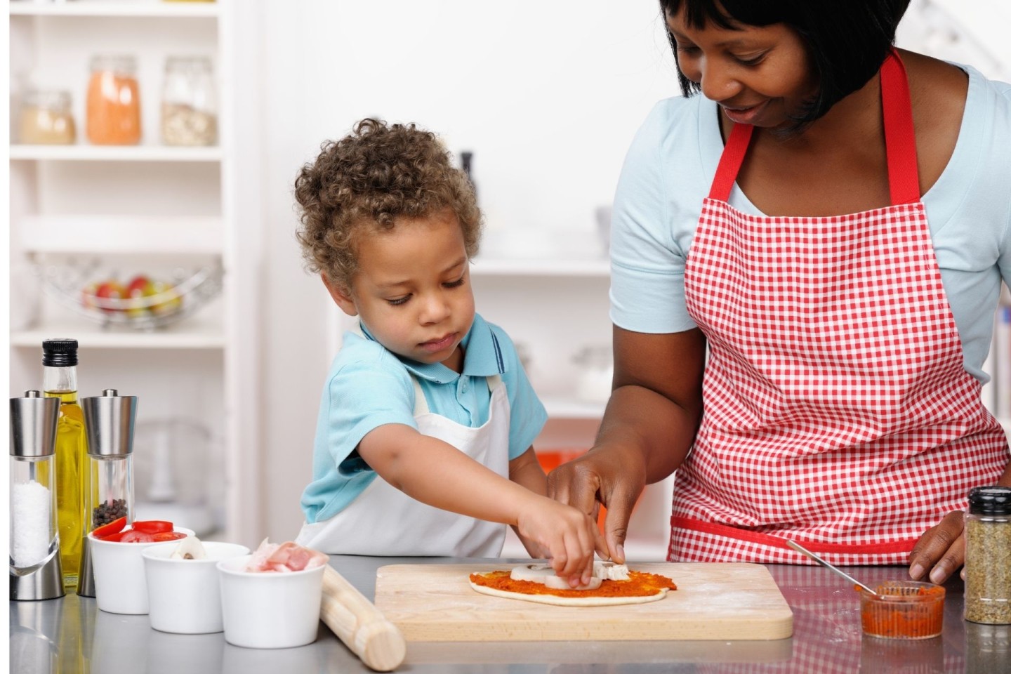 Toddler dinner idea: Mother and toddler making homemade pizza.