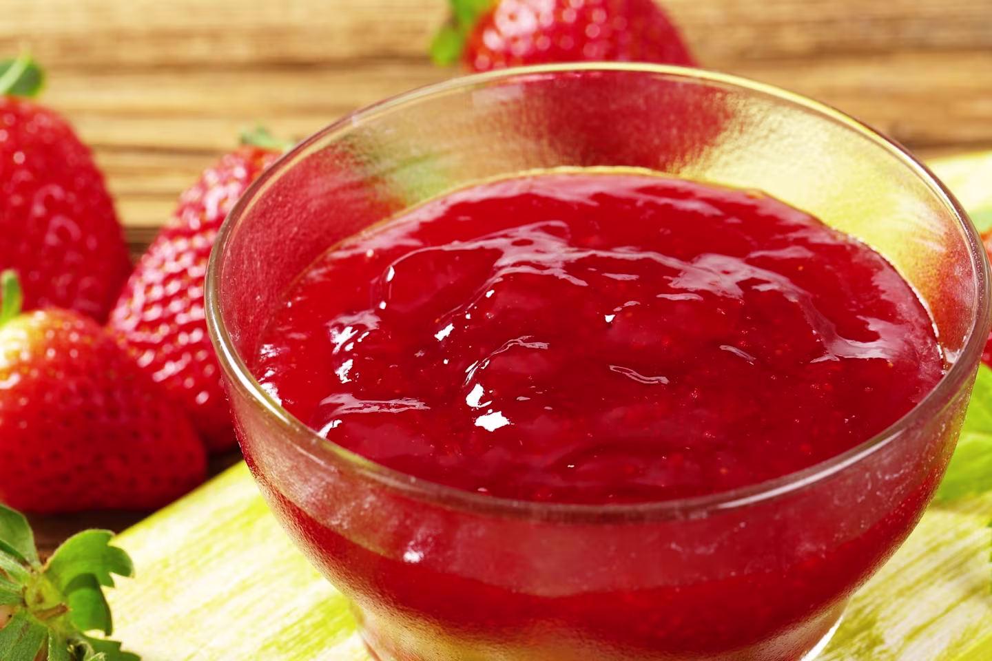 Glass bowl with strawberry puree surrounded by whole strawberries