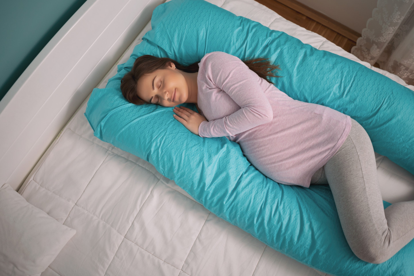 A woman using a U-shaped pregnancy pillow. 