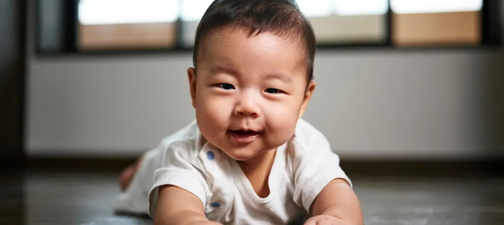 A baby smiling while lying down on their tummy.
