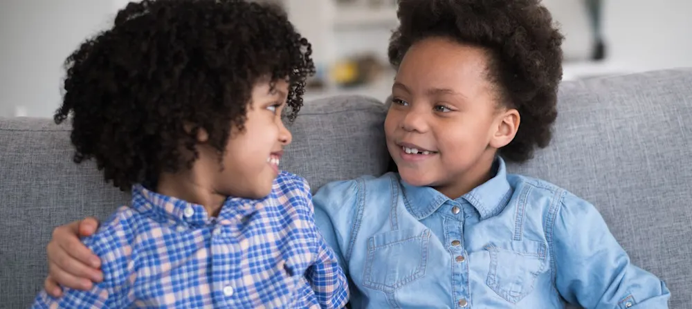 Two brothers sitting beside each other smiling.