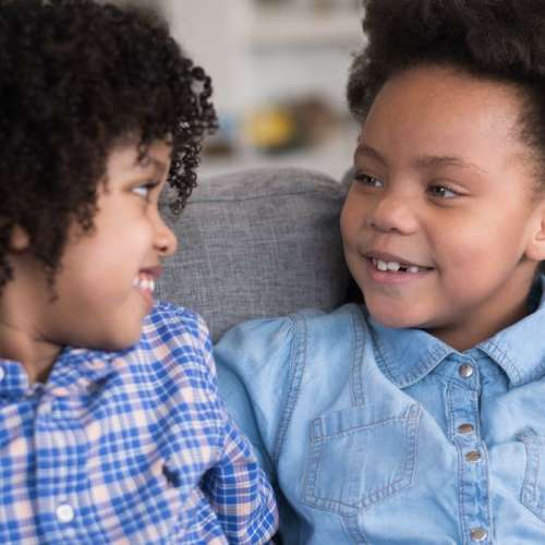 Two brothers sitting beside each other smiling.